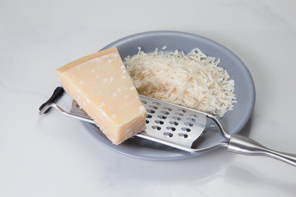 Wedge of parmesan next to a pile of freshly grated cheese on a plate with a grater