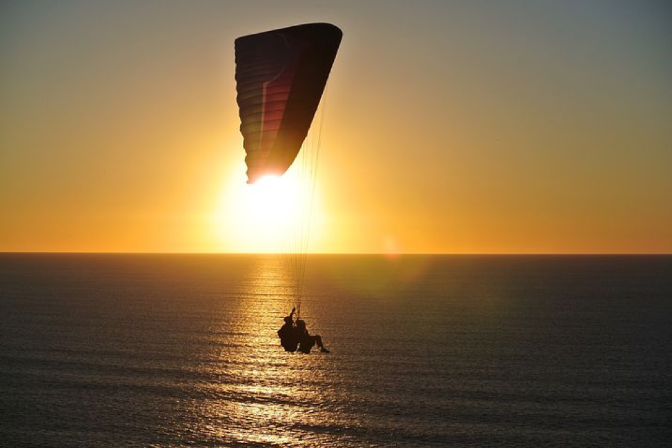 Parasailer silhouetted against an ocean sunset
