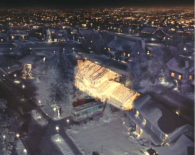 Aerial night view of a brightly lit house among a neighborhood of dark homes