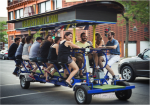 Large multi-seat party bike carrying a group of riders down a city street