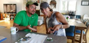 Two people smiling in a kitchen while sorting pieces of sea glass on the counter
