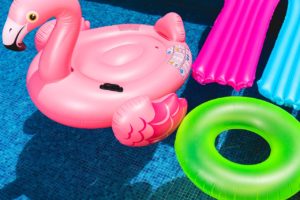 Inflatable pool floats, including a flamingo and a green ring, on the water